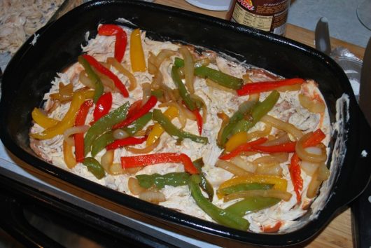 Add layer of shredded chicken and peppers and onions. Layers 5 & 6