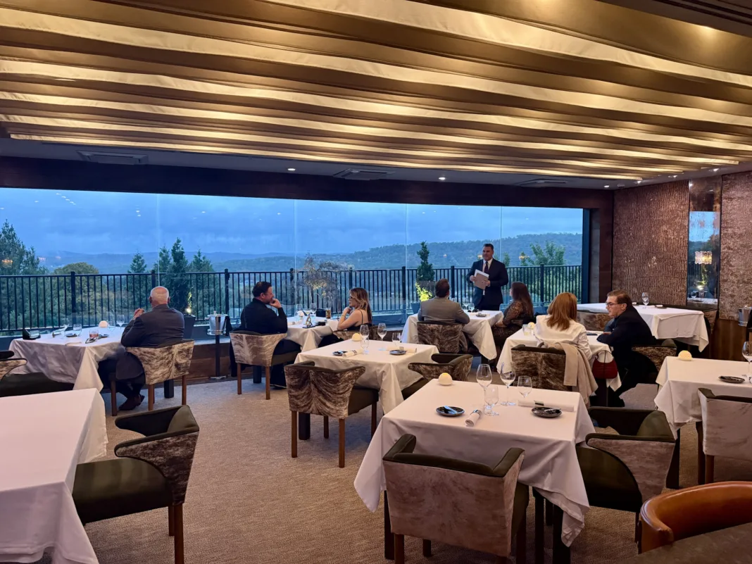 Restaurant Latour’s dining room with white-clothed tables and expansive windows overlooking wooded hills and mountain ridgelines.