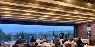 Restaurant Latour’s dining room with white-clothed tables and expansive windows overlooking wooded hills and mountain ridgelines.