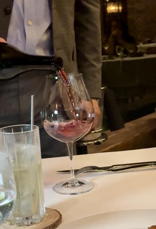 Wine being poured into a glass at a dining table at Restaurant Latour.