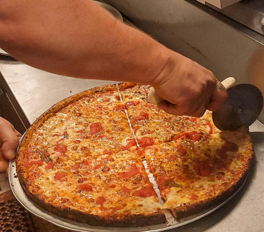 slicing pizza at Pizza Bowl