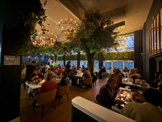 Main dining room at Olea Restaurant in Spring Lake with red velvet drapes and abundant greenery