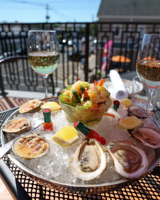 The Coastal Combo from Coastal Canteen features three freshly shucked oysters, three littleneck clams, three shrimp cocktail, and the restaurant's signature Sunset Ceviche, served alongside house-made corn tortilla chips for a fresh and flavorful raw bar experience.