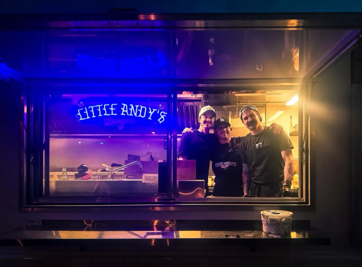 Team members posing inside the Little Andy’s Burgers food truck in Asbury Park, New Jersey, illuminated by vibrant neon lighting and serving handcrafted burgers in a late-night atmosphere