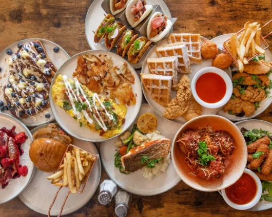 A table filled with a variety of dishes from the newly reopened OB Diner in Point Pleasant Beach, showcasing the diner's refreshed menu under Chef Diego Sanchez, including diner classics, elevated comfort food, and chef-driven specialties.