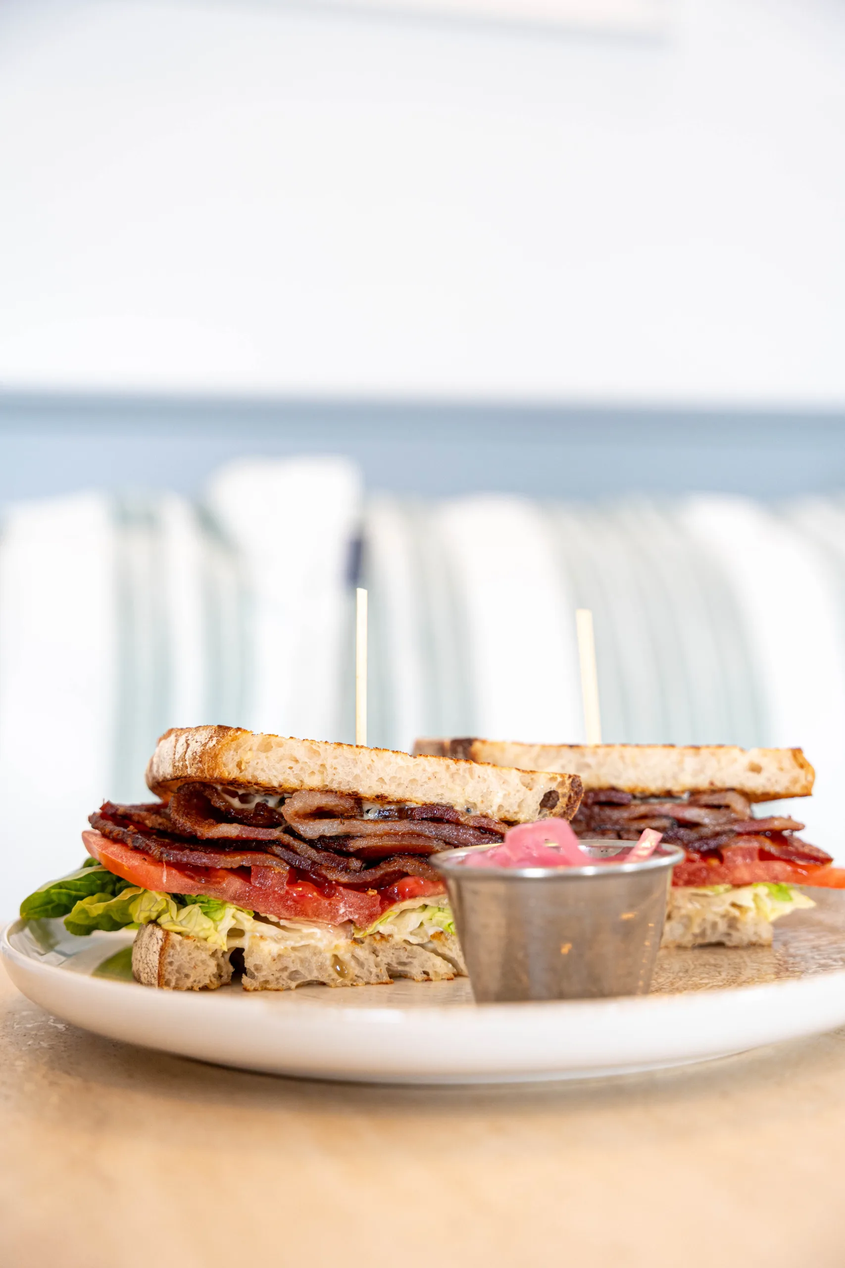 Classic BLT sandwich stacked with crispy bacon, fresh lettuce, and sliced tomato on toasted artisan bread, served with house-pickled onions at The Nest in Keyport, New Jersey.