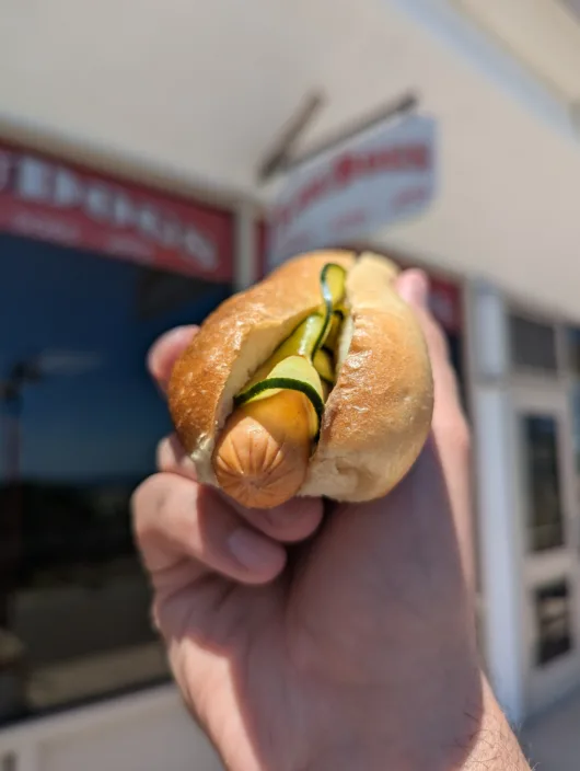 Lou Dogs Signature Hot Dog with Housemade Pickles A gourmet hot dog from Lou Dogs in Sea Isle City topped with housemade pickles on a freshly baked bun.