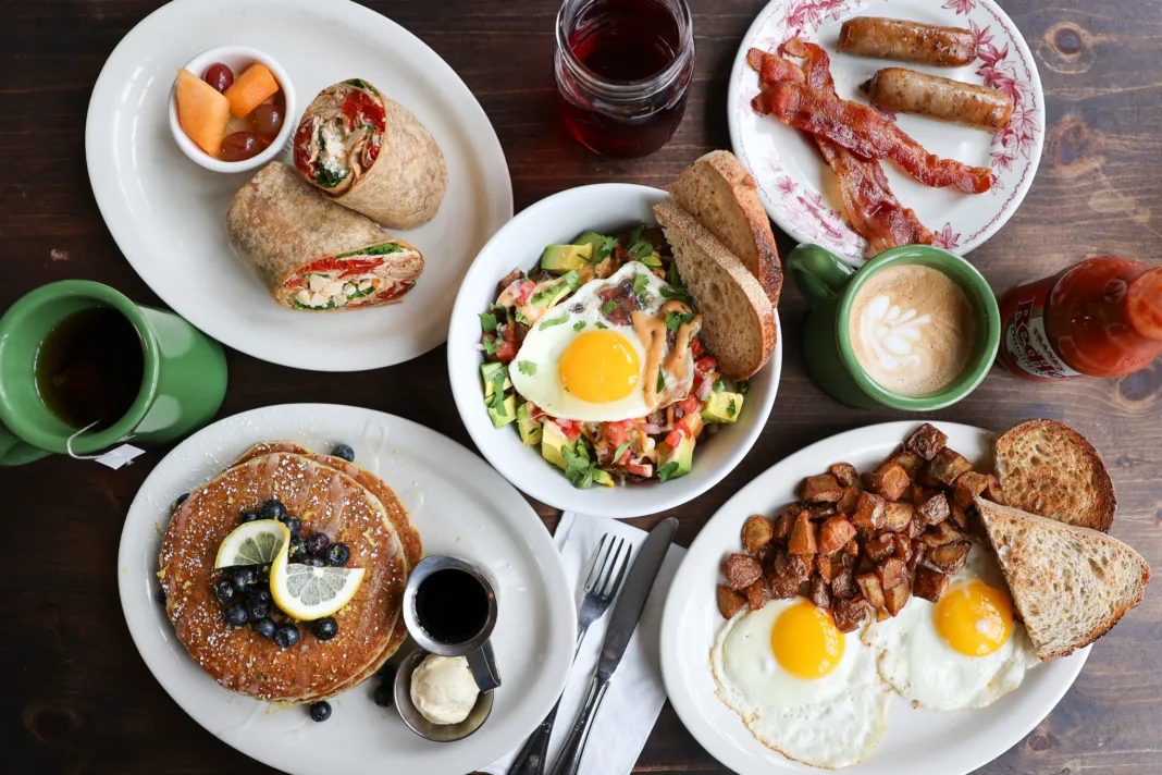 Colorful brunch spread featuring pancakes, eggs Benedict, avocado toast, fresh fruit, coffee, and mimosas at a New Jersey restaurant.