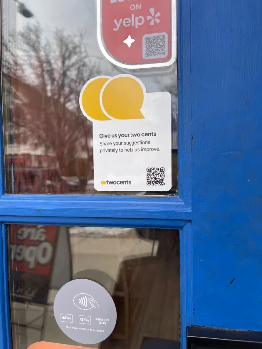twocents sticker displayed on a restaurant entrance inviting customers to share private feedback about their experience.