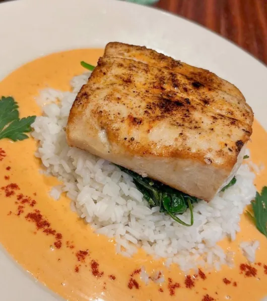 Pan Seared Mahi Mahi with coconut curry sauce, jasmine rice, wilted spinach, basil oil, and lime at SeaGrass Restaurant in Ocean Grove, NJ.