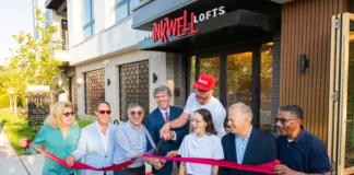 Group of people pose outside The Inkwell Lofts during a ribbon-cutting ceremony celebrating the opening of the venue.