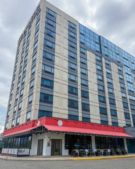 Exterior of Sheraton Lincoln Harbor Hotel with Beneci’s D’Italia Cucina awning and outdoor dining tables in Weehawken, NJ