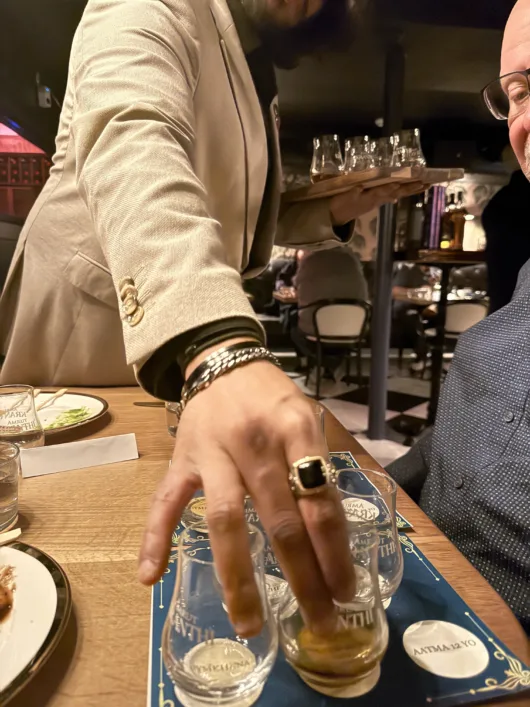 Server placing a whisky tasting glass on the table during a guided Amrut single malt tasting in Jersey City.