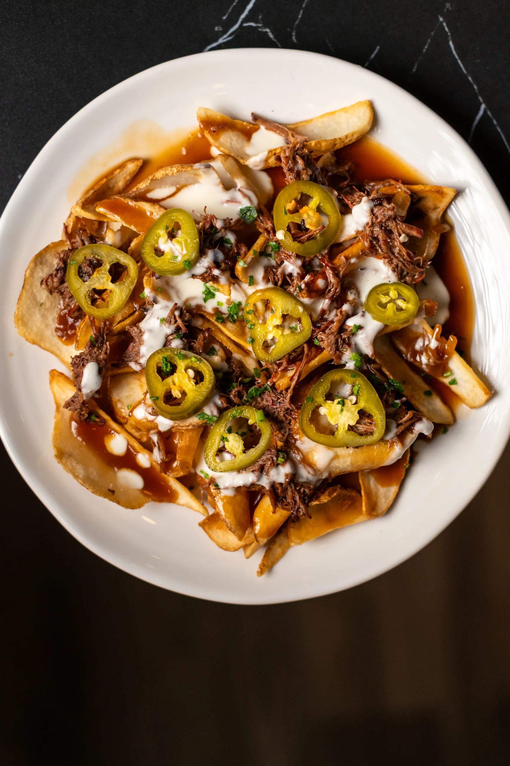 Loaded fries topped with shredded meat, melted cheese sauce, sliced jalapeños, and herbs at Luckies Bar & Grill.